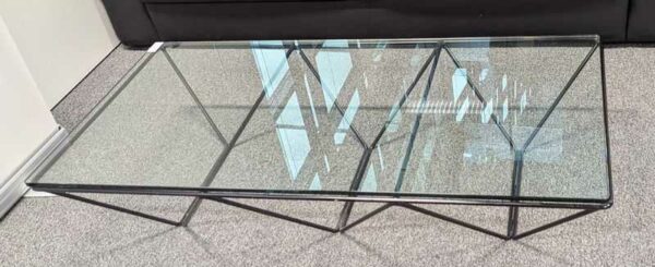 Table basse design Paolo Piva modèle Alanda, structure en acier tubulaire laqué noir, plateau en verre transparent. 26 x 120 x 60 cm. Localisation : 1 ouest