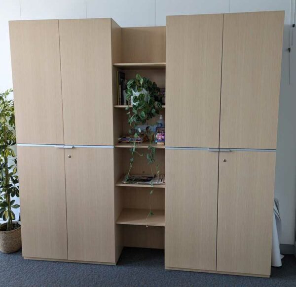 Armoire penderie en bois stratifié couleur chêne clair ouvrant par 4 portes. 218 x  226 x 43 cm. Localisation : 7 ouest