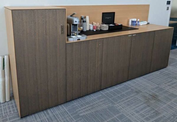 Buffet bas avec compartiment réfrigérateur intégrable en bois stratifié couleur chêne clair et chêne foncé ouvrant par 5 portes.  130 x 302 x 60 cm. Localisation : 7 ouest