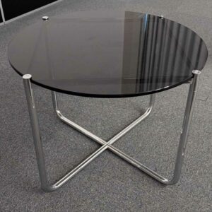 Table basse, plateau rond en verre fumé reposant sur piètement en X en acier chromé. Localisation : 7 est
