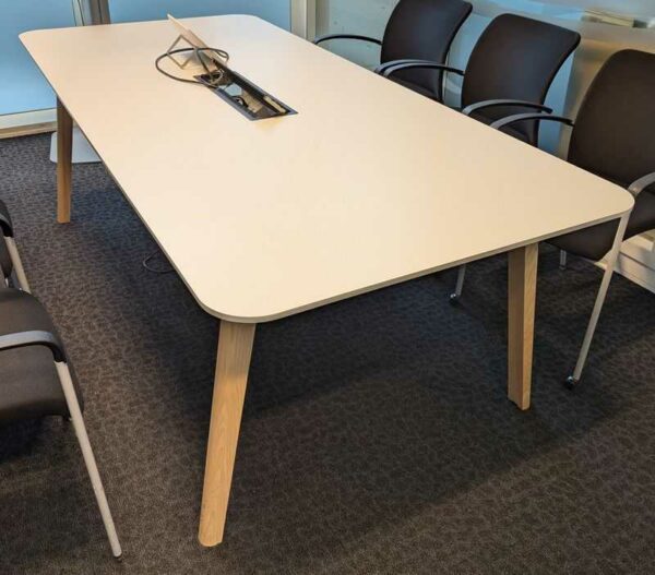Table de réunion, plateau rectangulaire à bords arrondis en bois stratifié blanc avec trappe passe câble, piètement oblique en bois naturel. 73 x 220 x 100 cm. Localisation : 7 est