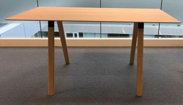 Table haute en bois couleur chêne clair, plateau rectangulaire reposant sur 4 pieds obliques. 104 x 200 x 90 cm. Localisation : 6 passerelle