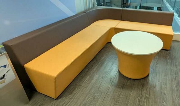 Espace d'attente de marque Connection comprenant 3 banquettes et 1 table ronde, en simili cuir orange et marron. 70 x 240 x 200 x 70 cm. Localisation : 5 ouest