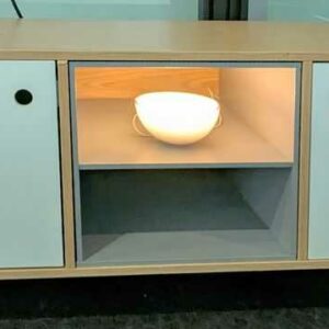 Meuble bas en bois couleur chêne clair avec une niche et 2 portes en bois laqué blanc ouvrant sur 1 étagère, piètement en épingle en acier laqué noir. 50 x 110 x 40 cm. Localisation : 5 ouest
