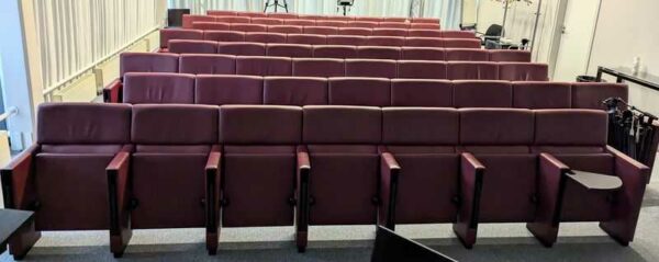 Rang de fauteuils de salle d'auditorium composé de 8 sièges en cuir bordeaux de marque POLTRONA FRAU avec tablette rétractable. 90 x 488 x 70 cm. Localisation : 7 est
