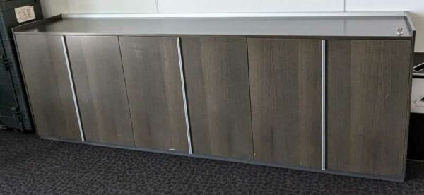 Armoire basse ou enfilade de marque BENE en bois foncé et inserts en métal ouvrant par 6 portes battantes. 82 x 240 x 47 cm. Localisation : 1 ouest