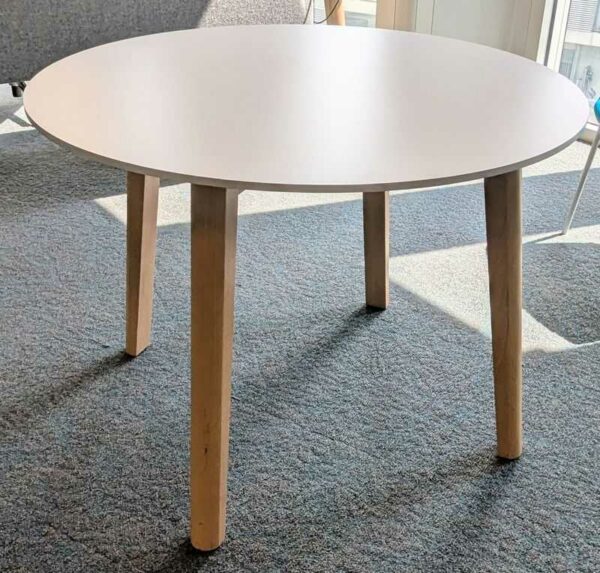 Table ronde en bois, plateau blanc reposant sur 4 pieds en bois naturel. 73 x 100 cm. Localisation : 5 est