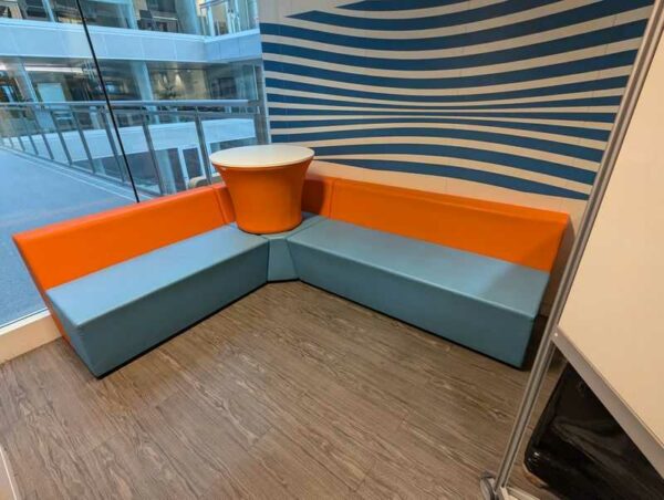 Espace d'attente de marque CONNECTION en simili cuir bleu et orange comprenant 3 banquettes dont une d'angle et une table. 108 x 160 x 180 x 70 cm. Localisation : 3 est