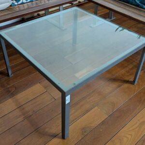 Table basse structure en fonte d'acier, plateau carré en verre transparent. 40 x 73 x 73 cm. Localisation : Canada hall