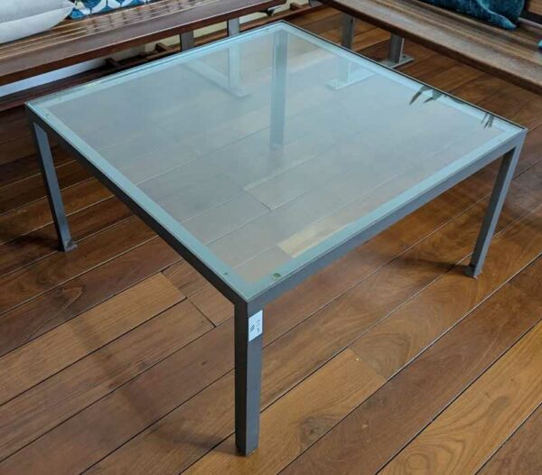 Table basse structure en fonte d'acier, plateau carré en verre transparent. 40 x 73 x 73 cm. Localisation : Canada hall