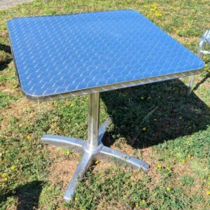 Table carrée de marque RODET en aluminium, plateau en bois stratifié revêtu d'inox. 73 x 70 x 70 cm. 6 unités. Vendu avec faculté de réunion. Localisation : extérieur