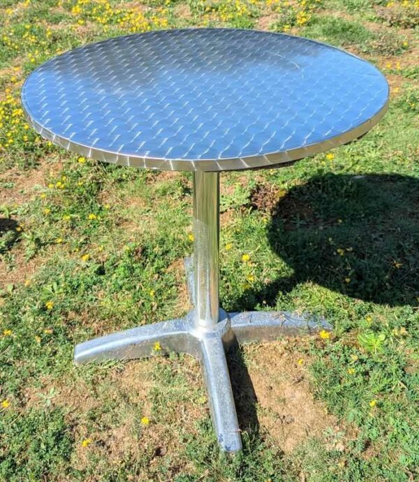 2 tables rondes de marque RODET en aluminium, plateau en bois stratifié revêtu d'inox. 73 x 70 (abimées). Localisation : extérieur