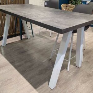 Table haute plateau rectangulaire en bois effet béton, piètement oblique en acier laqué blanc. 90 x 180 x 90 cm. Localisation : Theta 1er cafet