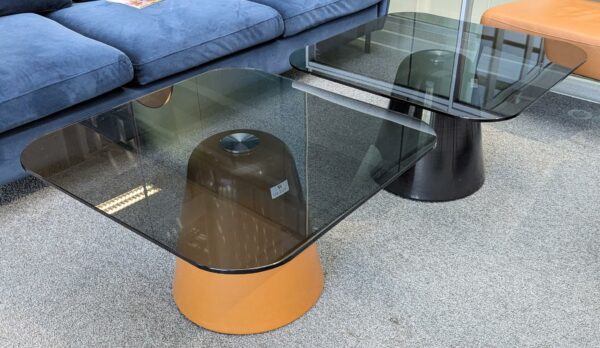 2 Tables basses, plateau carré à bords arrondis en verre fumé, piètement conique en métal, l'un marron et l'autre en noir. 40 x 70 x 70 cm. Localisation : 2 est