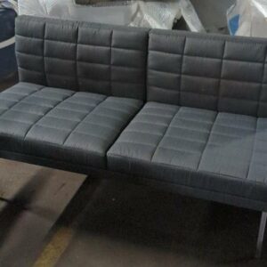Canapé de marque Geiger modèle Tuxedo recouvert de tissu matelassé gris, piètement en métal. 77 x 142 x 70 cm. Localisation : 8 rue de la Fossé aux Leux 91700 Ste Geneviève des Bois