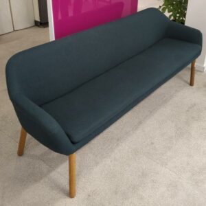 Canapé de marque Bolia recouvert de feutrine vert bouteille, coussin d'assise amovible, piètement en bois naturel. 77 x 202 x 57 cm. Localisation : 9 avenue Percier 75008 Paris
