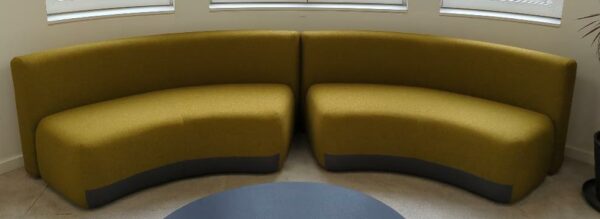 2 banquettes en arc de cercle de marque Viccarbe recouvertes de tissu chiné jaune et gris. 75 x 170 x 73 cm. Localisation : 9 avenue Percier 75008 Paris