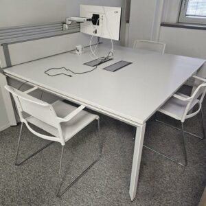 Bureau ou table carrée de réunion en bois blanc et piètement blanc. Equipé de deux trappes techniques. Dimensions: 160 cm x 160 cm. Quantités disponibles: 42 unités.
