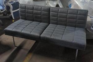 Canapé de marque Geiger modèle Tuxedo recouvert de tissu matelassé gris, piètement en métal. 77 x 142 x 70 cm. Localisation : 8 rue de la Fossé aux Leux 91700 Ste Geneviève des Bois