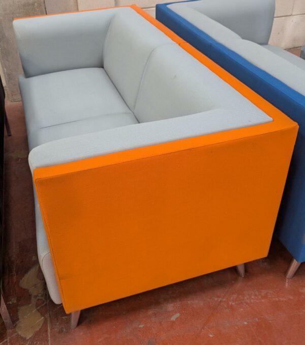 Canapé de marque Connection recouvert de tissu bicolore gris clair et orange, 4 pieds en acier chromé. 76 x 162 x 77 cm. Localisation : 8 rue de la Fossé aux Leux 91700 Ste Geneviève des Bois