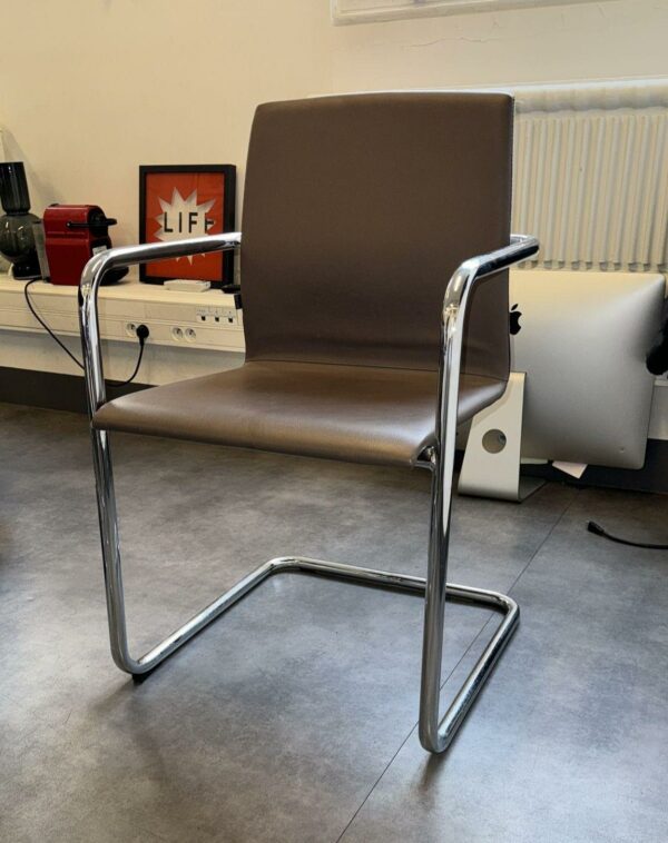 Fauteuil visiteur de marque Inclass, dossier et assise en cuir gris anthracite reposant sur un piétement en porte à faux en acier chromé. 85 x 53 x 56 cm. Localisation : 54 Avenue Philippe Auguste 75011 Paris