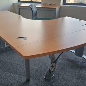 Bureau d'angle en bois couleur miel clair reposant sur un piètement métallique triple en acier gris. Dimensions: 160 x 160 cm. On y joint son caisson à hauteur d'appui. Quantités disponibles: 830 unités. Localisation : 8 av. de Lunca - 78180 Montigny-le-Bretonneux.