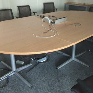 Table de réunion de forme ovale en 3 parties, plateau en bois stratifié couleur hêtre avec trappe technique, piètement en acier laqué gris. 75 x 320 x 180 cm. Localisation : 8 av. de Lunca - 78180 Montigny-le-Bretonneux. (5F02-1)
