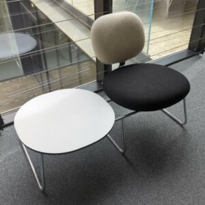 Espace d'attente design Jasper Morrison modèle Vega comprenant un siège recouvert de tissu noir et blanc et une table basse, plateau rond en bois blanc, structure en acier chromé. Largeur 114 cm. Localisation : 10 rue Petit - 75019 Paris (2eme)