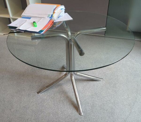 Table ronde plateau en verre transparent reposant sur un piètement à 4 branches en acier tubulaire chromé. 71 x 110 cm. Localisation : 6 rue Duret - 75116 Paris : 1-37