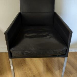 Fauteuil design Karl Friedrich Foster modèle Texas édition KFF recouvert de cuir noir, piètement en acier à section carrée, assise amovible. 86 x 53 x 53 cm. 26 unités. Vendu à l'unité avec faculté de réunion. Localisation : 6 rue Duret - 75116 Paris :  -1 salle à manger, 2eme bas, -2 vestiaire