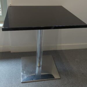 Table à plateau carré en bois laqué noir reposant sur un piètement en plexiglas biseauté, base en acier chromé. (usures). 73 x 70 x 70 cm. Localisation : 6 rue Duret - 75116 Paris : es 15