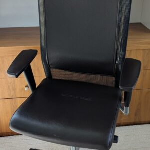 Fauteuil de direction pivotant ajustable avec tétière de marque TALIN, structure en acier chromé, dossier en résille, garniture en cuir marron foncé, piètement en étoile à 5 branches sur roulettes. Localisation : 7 ouest (7712)