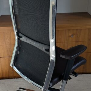 Fauteuil de direction pivotant ajustable avec tétière de marque TALIN, structure en acier chromé, dossier en résille, garniture en cuir marron foncé, piètement en étoile à 5 branches sur roulettes. Localisation : 7 ouest (7712) – Image 2