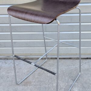 Tabouret haut coque en bois contreplaqué reposant sur une structure en acier chromé, piètement luge avec entretoise et repose pied. 88 x 42 x 52 cm. 7 unités. Vendu à l'unité avec faculté de réunion. Localisation: 10 rue du Ballon - 93160 Noisy-Le-Grand.
