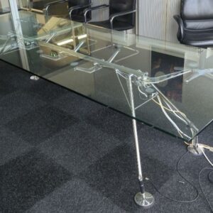 Table design Norman Foster modèle Nomos édition Techno, plateau en verre transparent, piètement en métal chromé. (éclat à un angle) 72 x 280 x 100 cm. (bât H rdc salle réunion BG vis)
