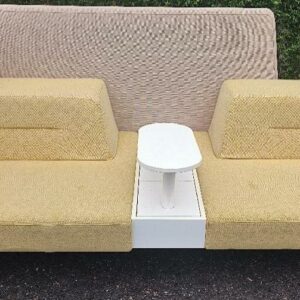 Banquette de marque Ophelis en tissu jaune et beige sur roulettes avec cloison haute, 2 assises, tablette centrale rotative, 1 trappe de rangement. 110 x 214 x 95 cm. Tablette rotative : 60 x 26 cm. Localisation : 30 rue Beauregard 60440 Nanteuil-le-Haudouin.