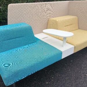 Banquette de marque Ophelis en tissu jaune, bleu et beige sur roulettes avec cloison haute, 2 assises, tablette centrale rotative, 1 trappe de rangement. 110 x 214 x 95 cm. Tablette rotative : 60 x 26 cm. (tâches et roue à revisser). Localisation : 30 rue Beauregard 60440 Nanteuil-le-Haudouin.