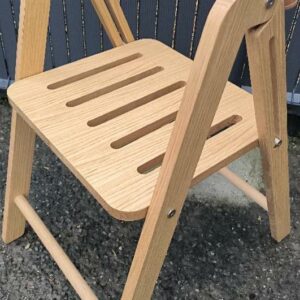 Chaise pliante de marque Ondarreta modèle Ika, structure en bois de chêne teinté naturel, dossier sangle en cuir camel. 79 x 46 x 59 cm. 15 unités. Vendu à l'unité avec faculté de réunion. Localisation : 30 rue Beauregard 60440 Nanteuil-le-Haudouin.