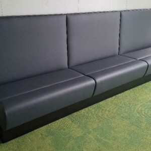 3 banquettes réunies par un socle en métal noir recouvertes de simili cuir gris anthracite. 110 x 300 x 65 cm. Localisation: Tour Coeur Défense - 92400 Courbevoie (TB4 3ème)