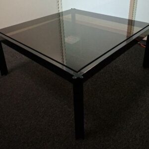 Table basse design George Ciancimino, structure en acier laqué noir, 4 pieds trèfles, plateau en verre fumé noir (petites rayures). 38 x 88 cm. 1 unité. Localisation: 6ème étage