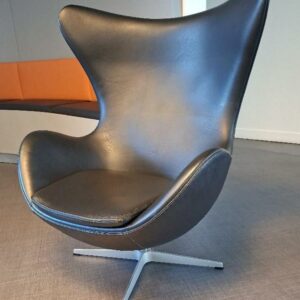 Fauteuil pivotant design Arne Jacobsen modèle Egg Chair édition Fritz Hansen recouvert de cuir noir, galette d'assise amovible, piétement en étoile à 4 branches en métal. 104 x 85 x 70 cm. 5 unités. Localisation: Accueil (3 unités) / Entresol local Ludothèque (2 unités)