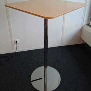 Table haute, plateau carré à bords arrondis en bois stratifie couleur hêtre, pied colonne en acier chromé sur pied colonne sur base circulaire. 111 x 65 cm. 4 unités. Localisation: 6ème étage salle 607