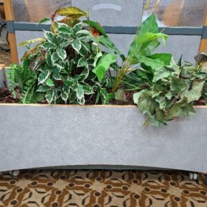 Jardinière sur roulettes en bois stratifié moucheté bleu avec plantes artificielles. 54 x 121 x 40 cm. 3 unités. Localisation: Rie