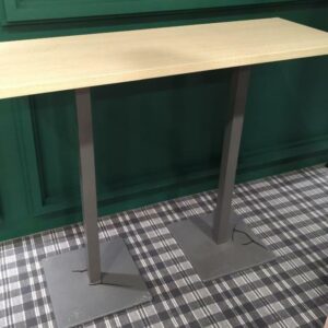 Table haute rectangulaire, plateau en bois couleur hêtre reposant sur 2 pieds colonnes à section carrée en métal. 103 x 130 x 45 cm. Localisation: Tour Coeur Défense - 92400 Courbevoie (cafet)