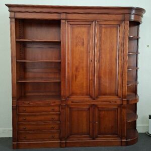 Meuble bibliothèque en bois couleur merisier en 3 parties, dont une à 3 étagères et 4 tiroirs, une ouvrant par 4 portes sur 4 étagères et un placard, et une partie en encoignure à  7 étagères. 243 x 235 x 41 cm. Localisation: BLB, 3 rue de la Fossé aux Leux - 91700 Sainte Geneviève des Bois