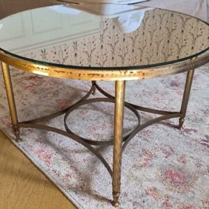 Table basse ronde en métal doré, plateau en miroir, pieds cannelés avec entretoise. Style Louis XVI. Dim : 40 x 63 cm. Localisation: BLB, 3 rue de la Fossé aux Leux - 91700 Sainte Geneviève des Bois