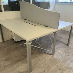 7 bureaux bench deux personnes, plateau en bois de couleur blanc avec trappe et séparateur de couleur gris, piétement en métal de couleur gris. Dim : 73 x 160 x 160 cm. Localisation : Alpine - 14 avenue des Tropiques - 91940 Les Ulis