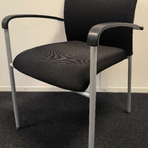 1 fauteuil dossier et assise en tissu de couleur noir, accoudoirs en plastique de couleur noir et piètement droit en métal de couleur gris. Dim : 83 x  55 x 56 cm. Localisation : Alpine - 14 avenue des Tropiques - 91940 Les Ulis