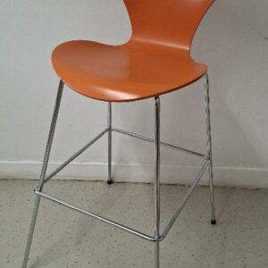 Chaise haute empilable design Arne Jacobsen modèle Série 7, édition Fritz Hansen, coque en bois laqué orange, piétement en acier chromé avec repose-pieds. 110 x 46 x 60 cm. Localisation: 54 avenue Philippe Auguste - 75011 Paris