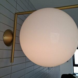 Applique murale design Michael Anastassiades modèle IC édition Flos, structure en laiton, globe en verre opalin blanc. 31 x 41 x 32 cm. Localisation: 48 rue Cambon - 75001 Paris